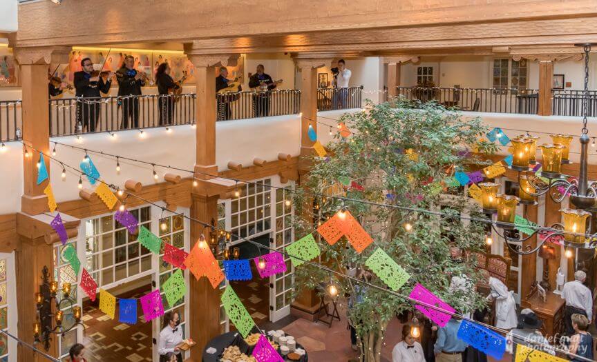 Guests enjoy a gathering in the decorated banquet hall while a mariachi band performs above.