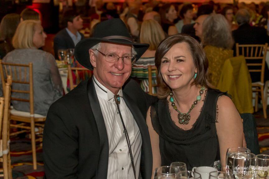 A smiling couple attends an elegant event in the grand banquet hall.