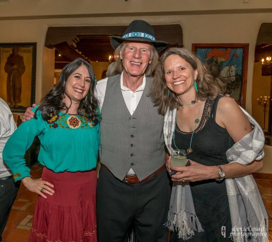 Three smiling guests pose together, enjoying the lively atmosphere of the event space.