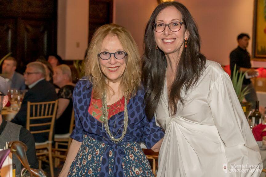 Two guests smile brightly while attending a reception in the elegant hotel banquet hall.