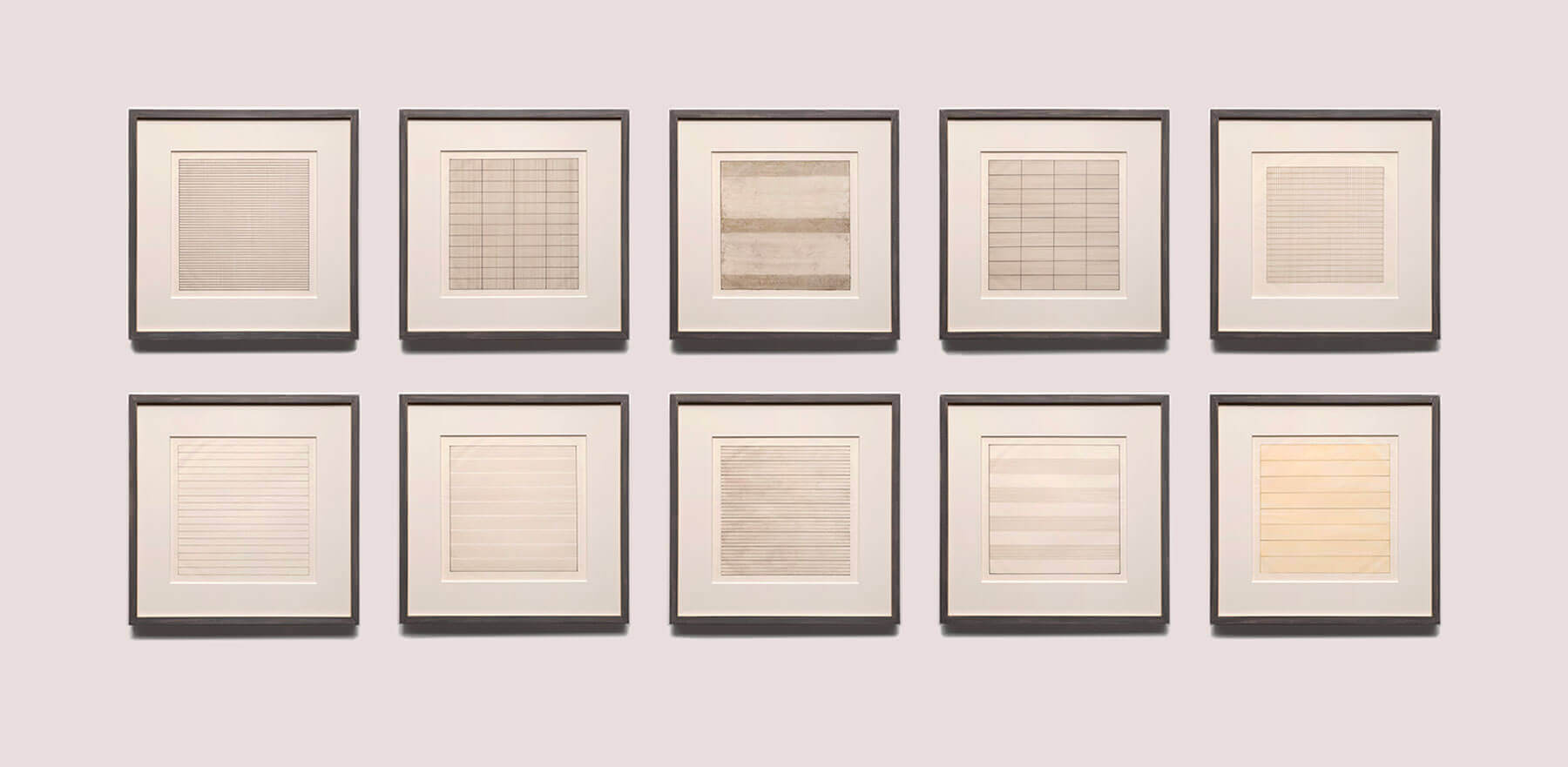 A gallery of ten framed minimalist prints featuring subtle lines decorates the wall of a boutique hotel.