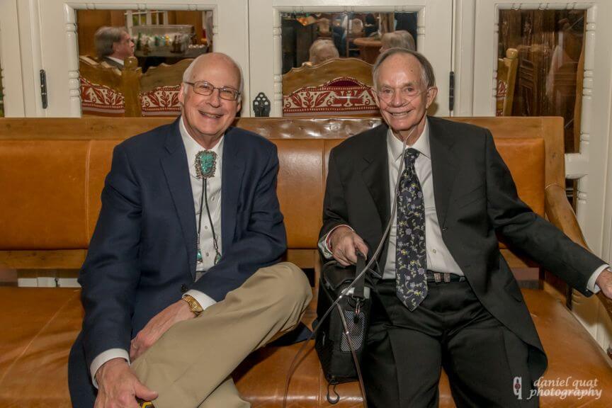 Two guests smile while seated on a leather banquette in the sophisticated banquet hall.