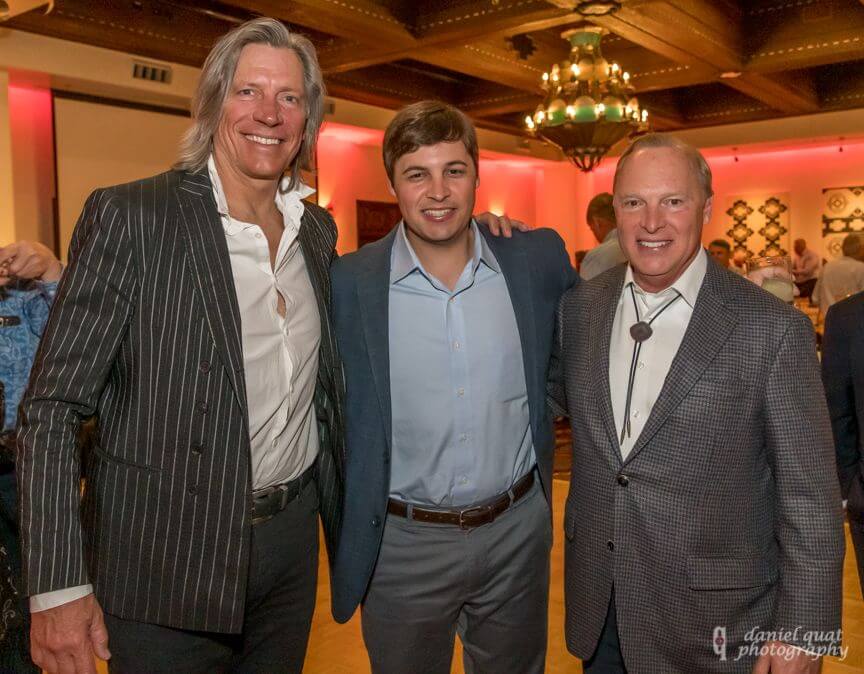 Three smartly dressed gentlemen pose together during an event inside the hotel banquet hall.