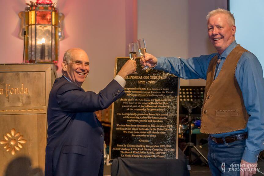Two smiling men raise a champagne toast during a celebratory event in the ballroom.