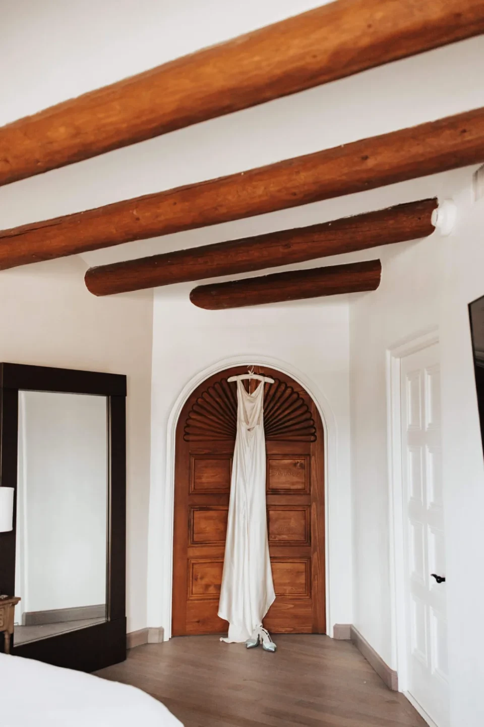 A satin wedding gown hangs on a carved wooden door inside one of our beautiful hotel rooms.