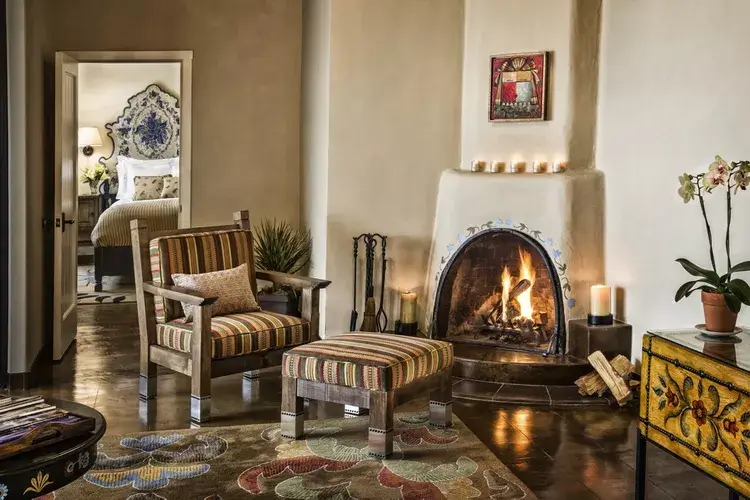 The rustic adobe fireplace illuminates the comfortable seating area of this luxurious hotel suite.