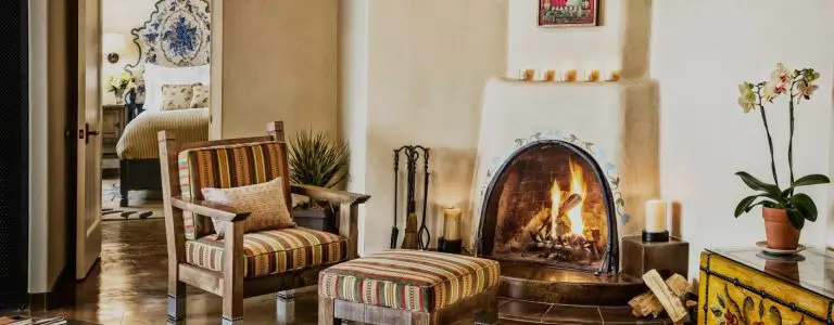 The elegant sitting area of one of the beautiful hotel suites features a cozy kiva fireplace and rustic chair.