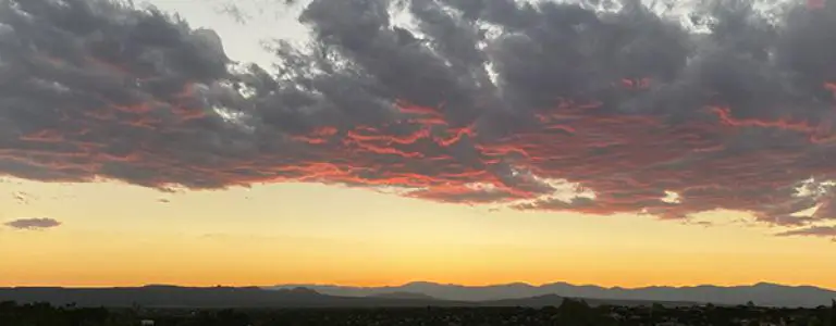 A breathtaking sunset viewed from the rooftop bar showcases pink clouds hovering over the distant mountains.