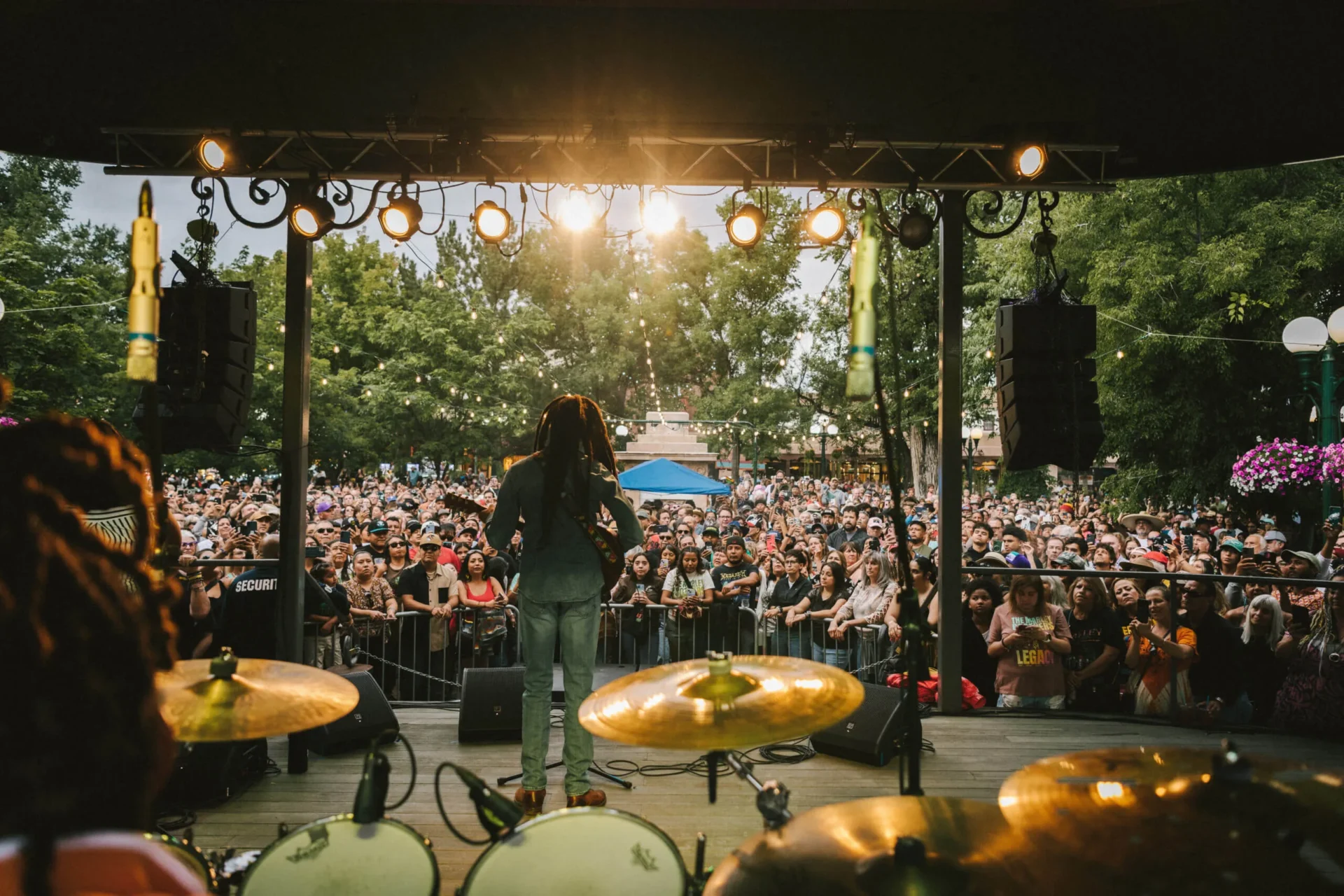 An artist performs on stage for a large, energetic audience at a vibrant live music event.
