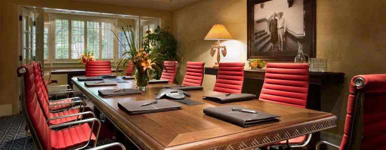 The executive boardroom offers a large wooden table, red leather chairs, and professional equipment for meetings.