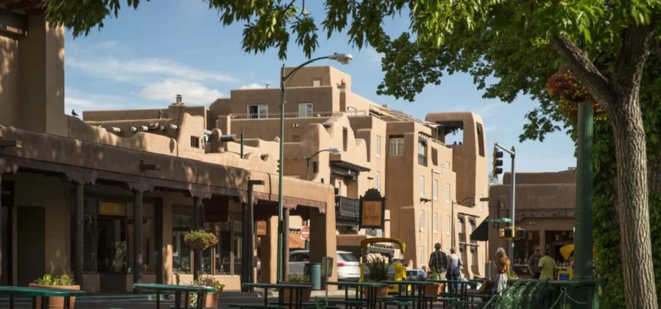 The adobe exterior of this large boutique hotel overlooks a tree-lined downtown plaza area.